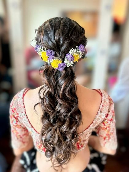 A messy, textured ponytail adorned with a crown of yellow and purple flowers. This is a chic and modern style for any wedding event.