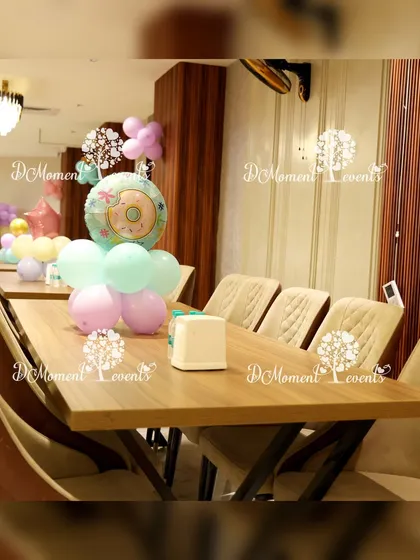 A simple table centerpiece for the Candyland party, featuring a donut foil balloon and a small cluster of pastel balloons.