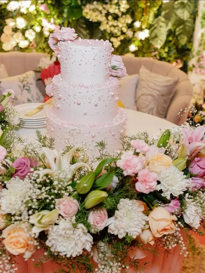 The cake deserves its own moment. I designed this display with the cake encircled by a lush arrangement of pastel roses, lilies, and baby's breath, making it a beautiful floral centerpiece.