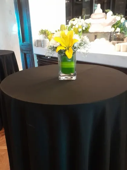 Simple elegance for any celebration. A clean cocktail table setup with a beautiful fresh flower centerpiece, showing our ability to handle all aspects of event decor.