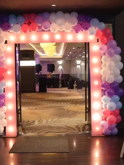 The entrance to Nyra's first birthday party, featuring a lit balloon arch and a welcome sign.