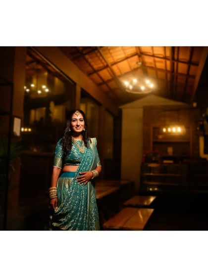 A beautiful portrait of the bride in a stunning teal gown for her Sangeet or reception, captured in warm, ambient light.