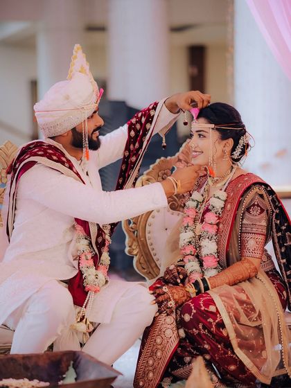 A candid moment during the wedding rituals. The groom's gentle gesture and the bride's happy smile show the deep affection between the couple.