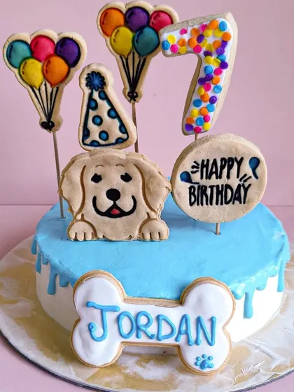 Jordan's 7th birthday cake in a cool blue. The design includes a party hat cookie, a colorful number 7, and a personalized name bone.