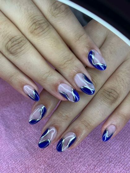 A modern design with a nude base, navy blue tips, and abstract silver chrome swirls.