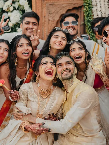 The couple surrounded by their friends, all sharing a moment of pure, unadulterated laughter during the Haldi. These are the memories that truly matter.