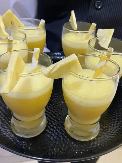 A close-up of our Guava Pineapple Blossom welcome drink. This refreshing beverage is garnished with a fresh slice of pineapple, offering a tropical start to the event.