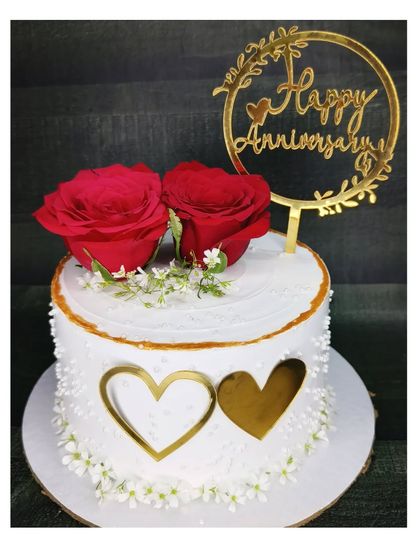 An elegant anniversary cake with fresh red roses and a golden heart design. This is a fresh pineapple cake, perfect for a classic and romantic celebration.