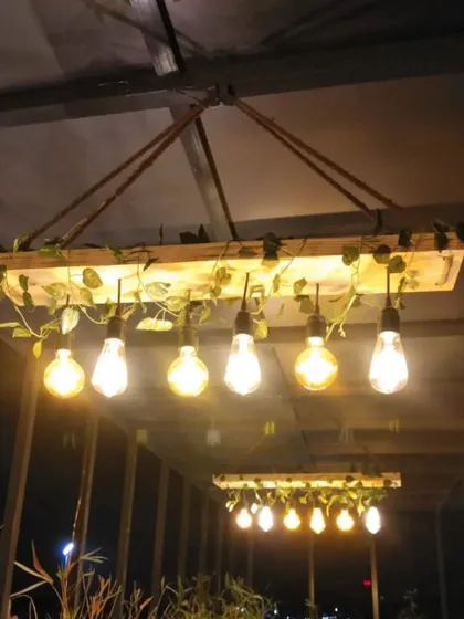 A custom-made rustic hanging light fixture, crafted from a wooden plank and Edison bulbs, perfect for a pergola or covered patio.