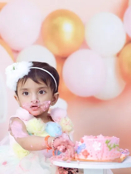 The aftermath of a successful cake smash. This little girl has frosting all over her face and is the picture of pure birthday joy.