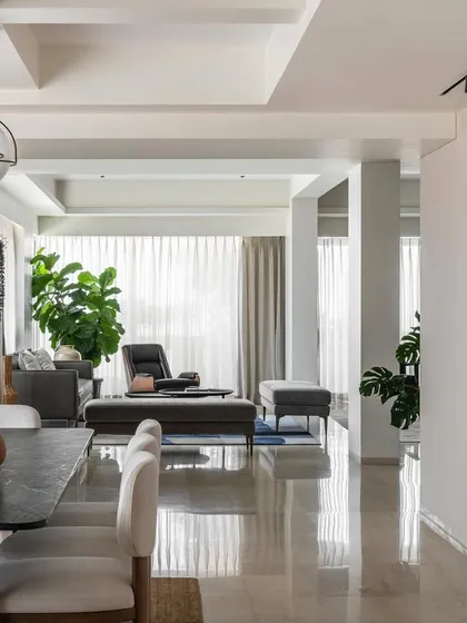 An open-plan view of Apartment 1600, showing how the dining and living areas flow together. The polished marble floor reflects light throughout the space, while curated furniture and art define different zones within the expansive, tropical-modern home.