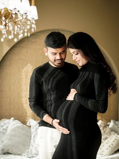 A classic portrait of the couple, both gently holding the baby bump, symbolizing their shared journey into parenting again.