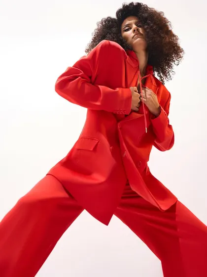 This image captures the dynamic energy of a bold red power suit. The wide-legged trousers and oversized blazer create a look that is both dramatic and effortlessly chic.
