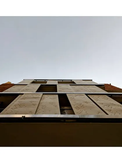 A view looking up at the facade, showing how the perforated screens create a dynamic and functional exterior. These shading devices are crucial for managing heat gain from the sun, which is a core principle of energy-efficient building design.