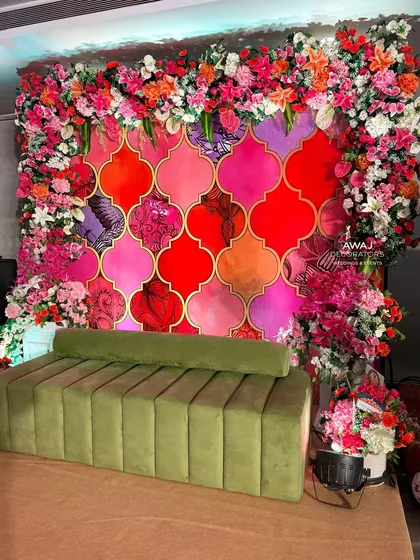 A side view of the main Mehendi seating, showing the plush olive green sofa and the rich floral border.