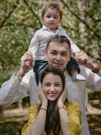 A playful family portrait with the son sitting on his father's shoulders.