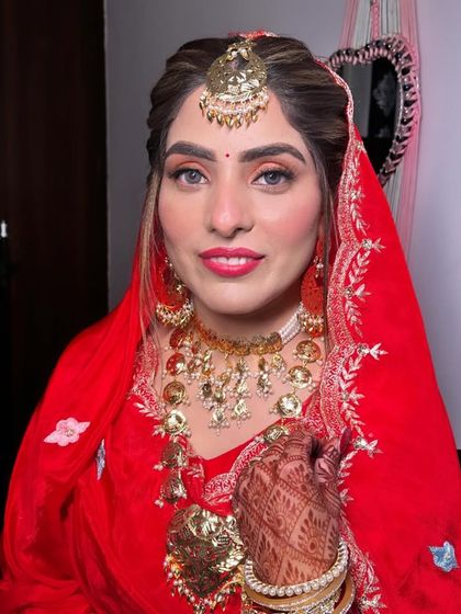 A beautiful Anand Karaj look. The makeup is fresh and radiant with a pop of color on the lips, complementing her traditional red suit.