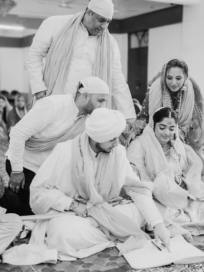 The signing of the marriage register during the Anand Karaj. This is a quiet, official moment amidst the spiritual ceremony, and I capture it candidly.