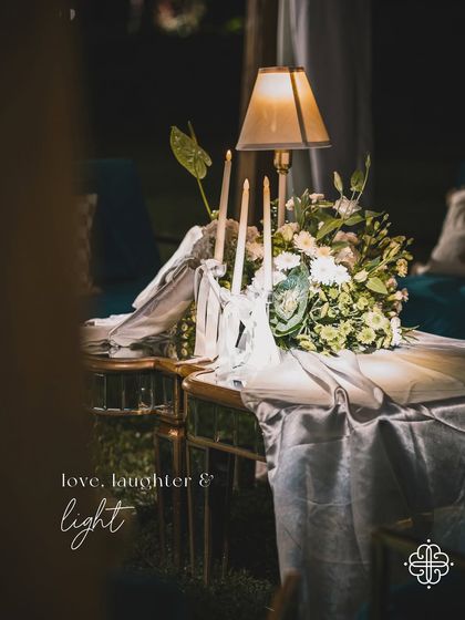 A table centerpiece with a lamp and a large silver bow, with the text overlay "love, laughter & light".