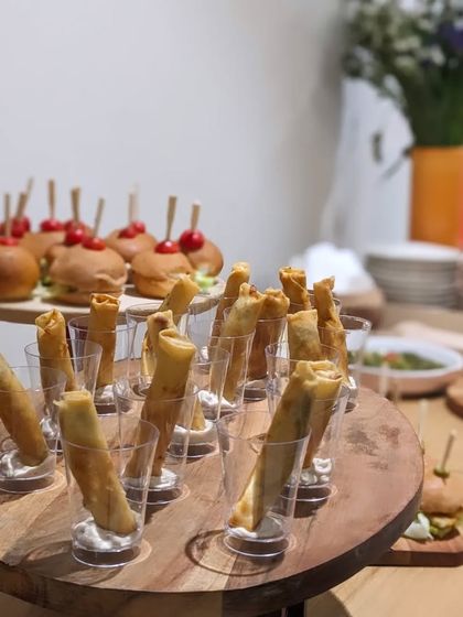 A beautiful display of my Truffle Cigar Rolls and mini burgers on tiered wooden stands. This showcases the variety of passed appetizers I can provide for any event.