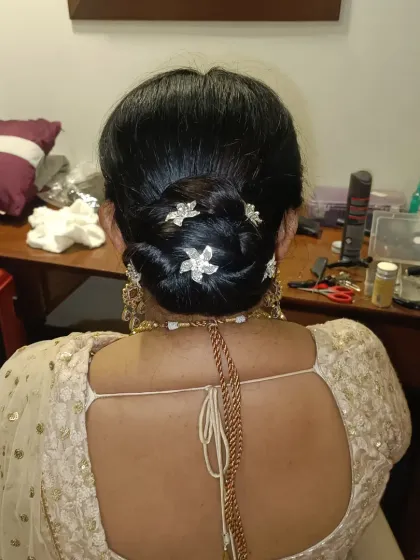 A clean and elegant low bun, intricately twisted and secured for a flawless finish. I adorned this classic updo with small, flower-shaped crystal pins for a touch of sparkle, making it ideal for a reception or formal dinner.