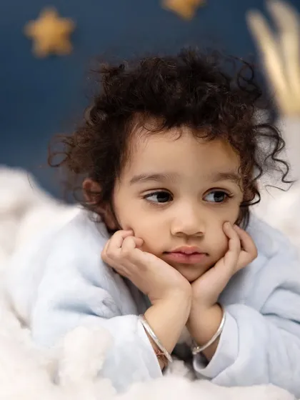 Lost in thought on a dreamy, cloud-filled set. This beautiful, contemplative portrait captures the quiet, gentle side of your child's personality.
