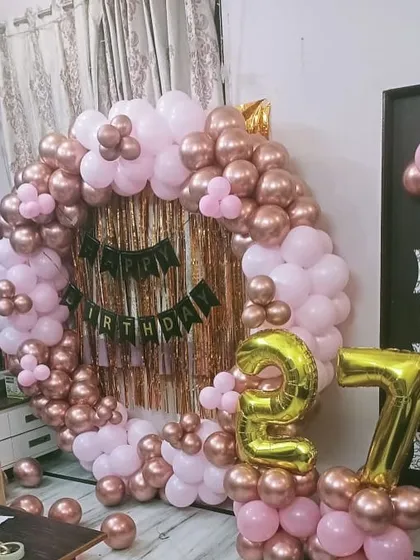 A full view of the rose gold and pink circular balloon arch for a 27th birthday. The foil number balloons add a personalized touch to this stylish setup.