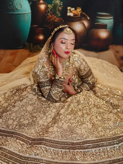 A dreamy, elegant shot of a bride in a golden sequin lehenga. The makeup is soft and romantic, with a classic red lip for a timeless finish.