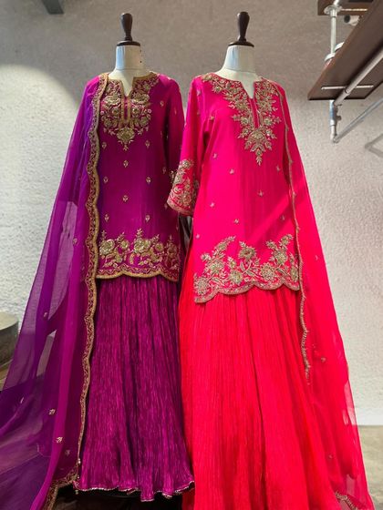 A beautiful pairing of magenta and fuchsia sharara sets. The detailed gold embroidery and flowing silhouettes make them a perfect choice for wedding festivities.