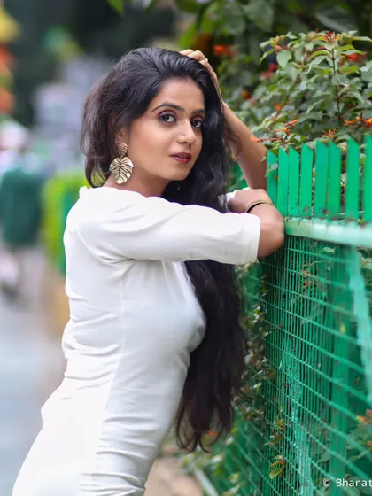 A three-quarter portrait against a green fence, with a direct and engaging look.