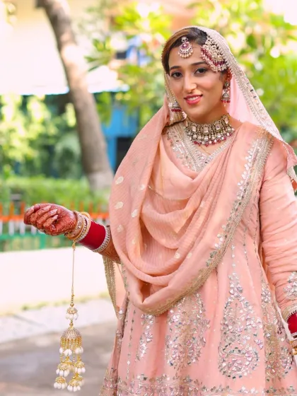 Holding her kalire, this Punjabi bride looks graceful and modern. The makeup is subtle, allowing her natural beauty and the soft colors of her outfit to shine.