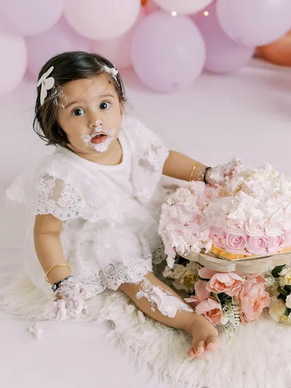 This little girl's expression is priceless. Covered in cake and looking right at the camera, this is a perfect, funny memory from her first birthday.
