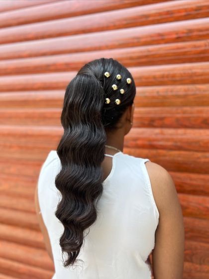 A modern and chic wavy ponytail, decorated with gold beads for a touch of glamour.