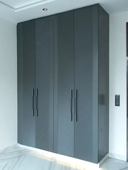 This four-door grey wardrobe provides a sleek, monolithic appearance, enhanced by subtle under-lighting that adds a warm, ambient glow to the room.
