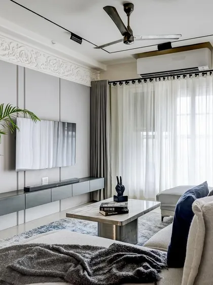 The living room of the 'YBJ Residence' is a study in European elegance and comfort. We used a soothing grey palette, a plush custom sofa, and clean lines to create a sophisticated yet inviting atmosphere. The ornamental moulding on the TV wall adds a classic touch to the modern space.