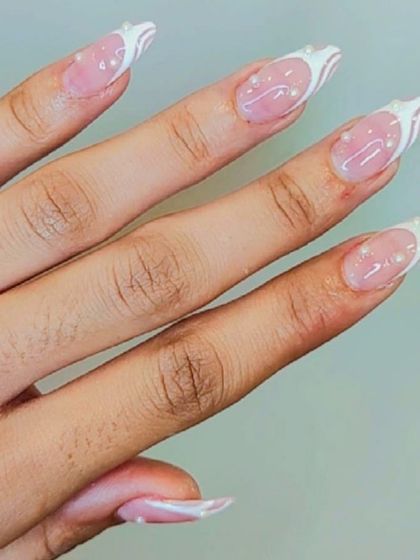 An elegant design with white swirls and pearl accents on a sheer pink base.