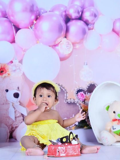 A full view of the first birthday cake smash setup with pink balloons and teddy bears.
