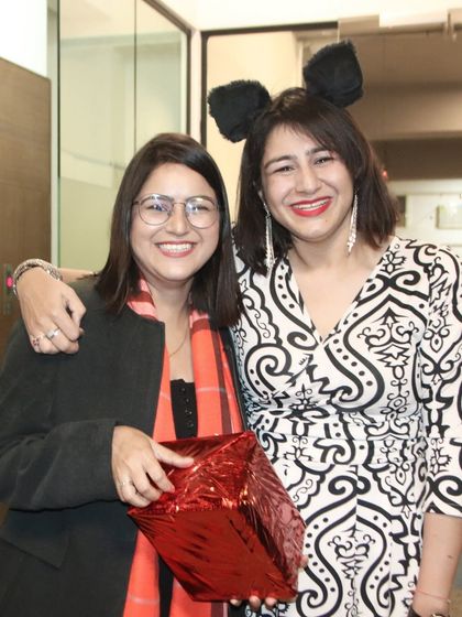 Two friends laughing and exchanging gifts at a Christmas party. I capture the joy and spirit of holiday celebrations.