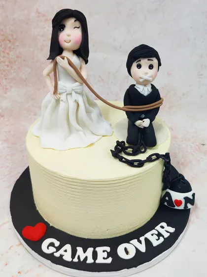 This cheeky "Game Over" wedding cake adds a touch of humor to the big day, featuring a bride playfully holding a leash attached to her groom.