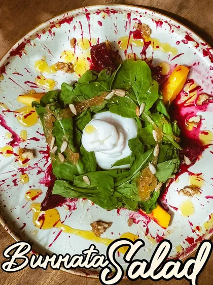 My Burrata Salad is a work of art. A creamy ball of burrata sits atop a bed of fresh greens, drizzled with a tangy vinaigrette and a splatter of beet puree.