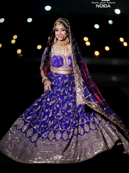 A full-length shot of a bride in a royal blue and gold lehenga, showcasing a complete look against a dramatic background. This is the kind of portfolio shot that gets you noticed.