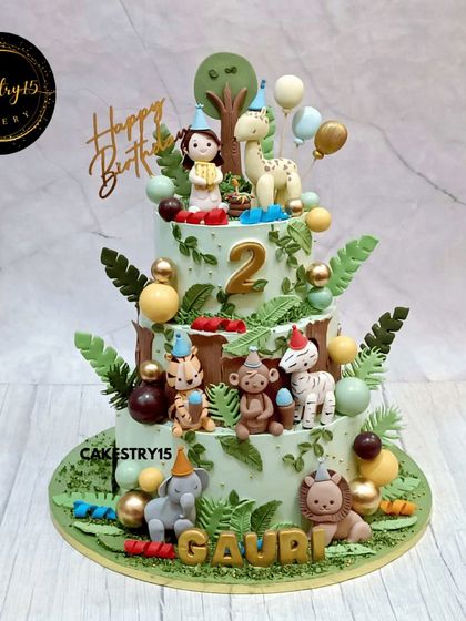 A grand three-tier safari-themed cake for a second birthday. This 6kg chocolate cake is teeming with life, featuring a girl, a giraffe, and numerous other party-hat-wearing animals.