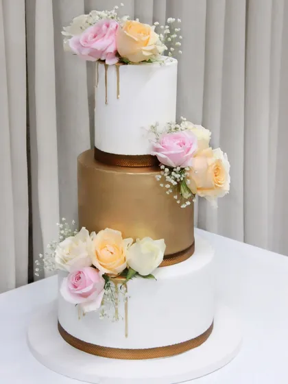 A beautiful three-tiered wedding cake in white and gold with a gold drip effect, pulled off in just a day and a half for a last-minute order.