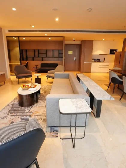 An angled view from the corner of the living room, showing the flow from the seating area to the dining space and kitchenette in the background.