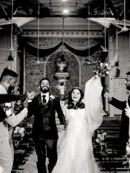 A classic "just married" exit from the church, with guests cheering and taking photos. The black and white gives it a timeless, documentary feel.