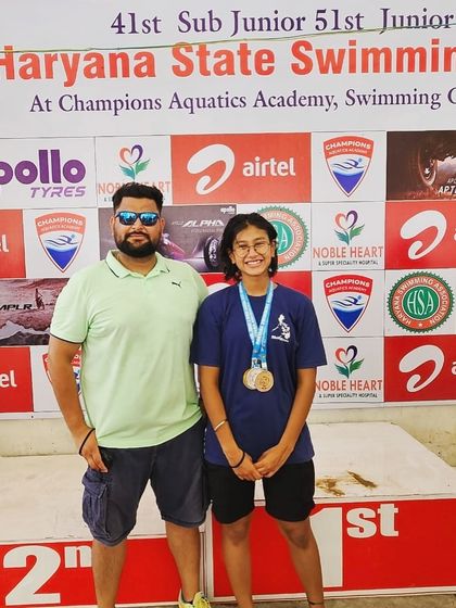 Standing with Prapti Ghose after she won 4 gold medals at the Haryana State Open Championship. She dethroned the reigning best swimmer on her home ground, proving her mettle.