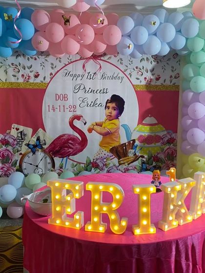 An "Alice in Wonderland" inspired first birthday for Princess Erika, with a themed backdrop, pastel balloon arch, and light-up letters.