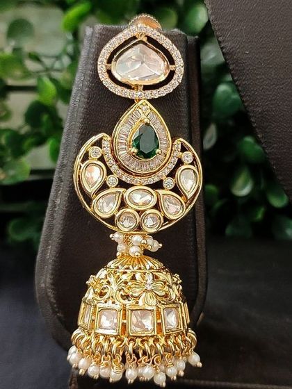 A magnificent kundan jhumka with a pear-shaped top and a large, ornate bell.