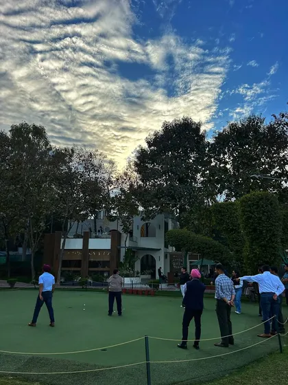 A group of people enjoys the putting green under a sky filled with incredible clouds.