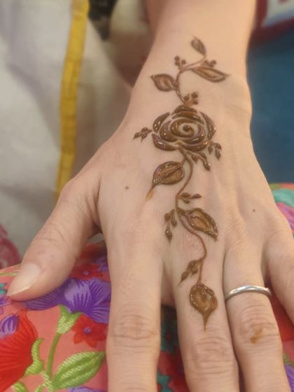 A single, elegant rose vine trailing down the back of the hand. This is a classic and timeless minimalist design that is perfect for any occasion, from a party to a casual get-together.